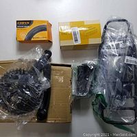 Lot photo showing a bicycle back seat or basket holder frame, boxed inner tubes, and other components in plastic packaging