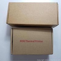 Two plain brown cardboard boxes stacked, top box larger and bottom box labeled 'MINI Thermal Printer' in red text.