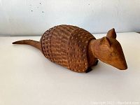Side view showing full length of carved armadillo with textured shell and elongated tail.