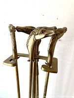 Close-up of the four fireplace tool handles sculpted as horse heads in brass.