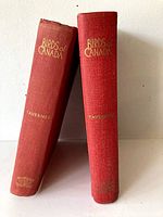 Two red hardcover books titled Birds of Canada by Taverner, showing spines with gold lettering, one leaning on the other, visible wear on the bottom spine of one book.