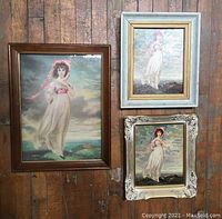 Overview shot of the three vintage framed prints hung on a wood-paneled wall, showing different frame styles and sizes