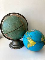 Two vintage globes, one larger metal with stand, one smaller blue without stand