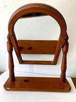 Front view of vintage solid pine swivel mirror showing natural wood finish, turned supports, and arched mirror glass.