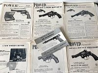 Overhead image showing five individual Smith & Wesson paper advertisements from the 1950s arranged on a flat surface. Ads feature black & white handgun pictures and text.