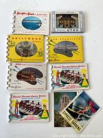 Photo showing the front covers of the 7 miniature tourist books, featuring locations like Hampton Beach, Scenic Utah, Hollywood, San Francisco, Reno, Winter Haven, and Cypress Gardens.