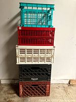 Stack of 5 plastic crates showing varied colors and brands including Tuscan and Dollywood.