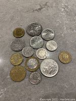 Top view of 12 French Franc coins laid out on a flat surface. Shows variety of sizes and colors, small gold/brass toned coins and larger silver toned coins.