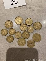 Photo showing 14 gold-colored Finnish coins arranged flat with obverse side showing Finnish heraldic lion and inscriptions including the year.