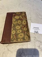 Front cover of antique French poetry book with marbled paper and brown leather spine, showing wear on edges.