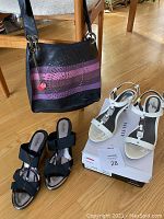 Photo showing Desigual black and purple crossbody purse, black wedge slides size 10, and cream Alfani heels size 10 placed on a wooden floor.