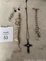 Full display showing all items: black cross necklace, two bracelets, and four earrings arranged on flat surface.