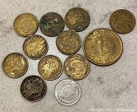 Top view of 12 French coins showing front face with denomination, dates, and some portrait details. Coins appear brass/bronze with varying patina and wear.