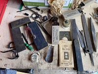 Wide shot of antique electrical parts, metal tools, old cabinet wheels, metal blades and boxed electrical components on workbench