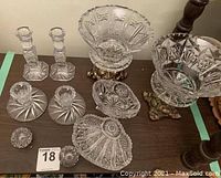 Full view of all crystal pieces including candlestick holders, footed bowls on brass stands, tripodal bowl, and smaller decorative pieces.