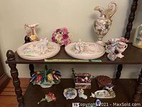 Shelf with two 3D porcelain wall plaques, ceramic basket with multicolored tulips, small vases, bird figurines, and other porcelain items.