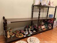 Full view of wooden two-shelf display shelf holding various small decorative figurines and plates, showing overall size and style.