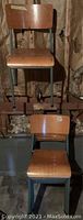 Photo showing two vintage school chairs against a basement wall with insulation exposed, illustrating wood and metal construction.