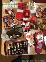 Top-down image showing assortment of vintage Christmas decorations including Santa figurines, nativity scene figures, candle holders, and table linens.