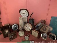 Group of vintage clocks and telephones, including rotary phones and multiple desk alarm clocks