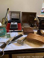 Vintage men's and women's grooming items including combs, brushes, scissors, razors, and bottled grooming liquids arranged on towel.