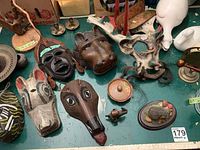 Overview of table top with multiple wood masks, small figurines, faux flowers and other decorative items.