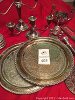 Wide view of assorted silverplate trays, candelabras, and tableware on red background