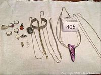 Full lot of jewelry items laid out including rings, necklaces, cuff bracelet and charms.