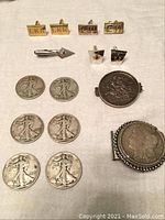 Six Walking Liberty half dollars, Masonic and engraved cuff links, money clip and coin pin laid out on fabric