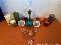 Collection of assorted candles and candleholders displayed on wooden surface