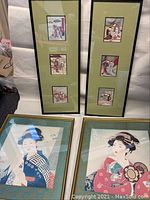 Photo showing the set of four framed Japanese artwork prints featuring geisha girls, including two large square frames and two tall frames with three smaller prints each.