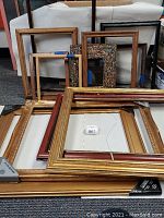 Photo showing a mix of gold plated, colorful decorated and wooden picture frames in various sizes.