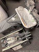 Overview of both assembled playards, one with bassinet, highlighting materials and included toys as well as carry case on floor.