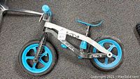 Side view of Chillafish BMXie child's balance bike, showing blue wheels, grey and black frame, handlebar and seat.
