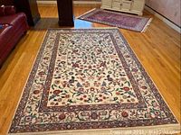Full view of floral patterned rug on hardwood floor showing overall design and condition