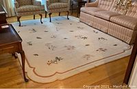 View of entire off-white floral area rug under furniture, showing size and pattern.