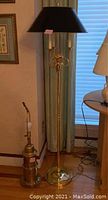 Photo showing full view of both brass lamps, floor lamp with black shade and table lamp without shade, capturing size and metal condition