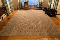 Full view of the large area rug in a room showing overall size, faded floral design, and wear spots.