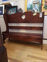 Front view of dark brown wooden bench with heart cutout and horizontal slats on backrest.