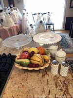 Lot arranged on kitchen counter showing all items including milk glass hobnail pieces, ceramic fruit bowl, and clear glass cake plate.
