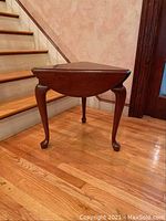 Side view image showing the engraving style legs and smaller triangular top with leaves down.