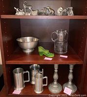 Shelf with all pewter items, glass shoe and pitcher visible