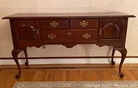 Front view of the Knob Creek wooden breakfront showing three drawers with brass pulls and two cabinets with panel doors on cabriole legs with claw feet.