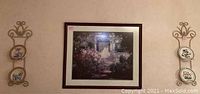 Two wall hanging plate racks each holding two decorative plates on the wall with framed wall art print in center