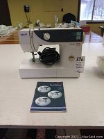 Full view of Pfaff Hobby 1016 sewing machine with attached power cord and instruction manual laid flat in front.