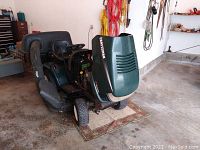 Front-three-quarter view showing Craftsman green hood, steering wheel, seat and clipping bucket