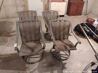 Four metal patio chairs arranged on a basement floor, showing overall condition and style.