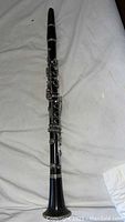 Full length of Robert Thibau clarinet showing black plastic body with silver keys and bell.