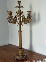 Full view of the tall heavy 7-stick candle holder with detailed column base and visible ornate arms.