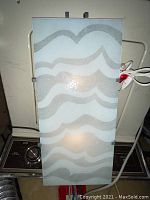 Front view of the wall mounted lamp showing frosted glass shade with wavy gray pattern illuminated from inside.